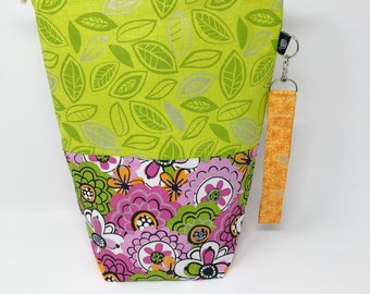 May include: A green and pink drawstring bag with a floral pattern. The bag has a matching orange strap with a silver clip.