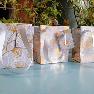 3 piccole buste regalo in carta laminata grigia e oro con etichette regalo abbinate, simboli della fortuna 2, buste regalo fatte a mano