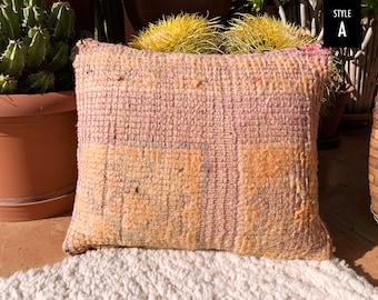 May include: A soft, woven pillow with a pink and beige color scheme. The pillow has a textured surface and a slightly frayed edge.