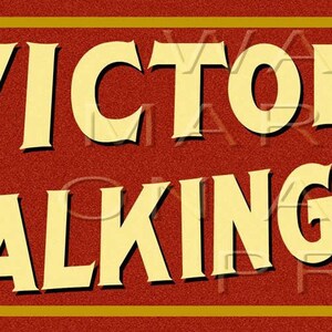 May include: A rectangular sign with the words "VICTOR TALKING MACHINES" in large, cream-colored letters. The background is a textured red with a gold border. A circular logo features a dog listening to a gramophone.