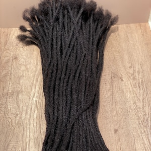 May include: A bundle of black synthetic dreadlocks, likely for hair extensions. The dreadlocks are neatly arranged and appear to be of good quality.