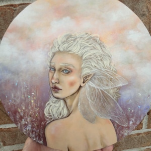 Puede incluir: Pintura redonda de una mujer con piel pálida, cabello blanco y ojos azules. Tiene alas delicadas y translúcidas y está situada sobre un cielo suave de colores pastel. La obra evoca un tema de fantasía.