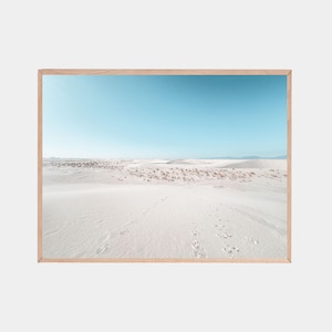 Peut inclure: Impression sur cadre d'un paysage désertique avec des dunes de sable blanc sous un ciel bleu clair. Le cadre en bois naturel met en valeur les traces de pas dans le sable.