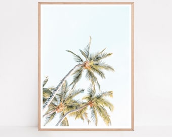 May include: A framed print of three palm trees against a bright blue sky. The trees are silhouetted against the sky, with their fronds reaching up towards the sun.