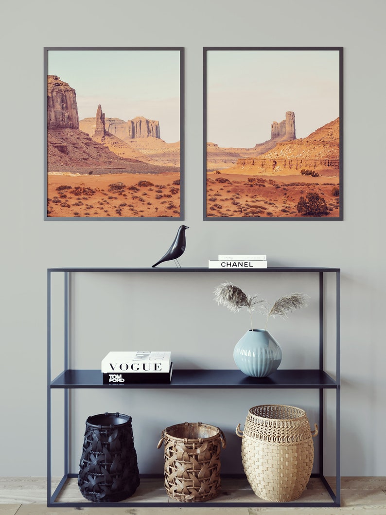 Peut inclure: Deux photographies de paysage encadr&eacute;es d'une sc&egrave;ne d&eacute;sertique avec des formations rocheuses rouges. Une &eacute;tag&egrave;re noire &agrave; deux niveaux contient une figurine d'oiseau noir, un livre blanc avec le mot "VOGUE" sur la couverture, un vase bleu avec des fleurs s&eacute;ch&eacute;es et trois paniers tiss&eacute;s.