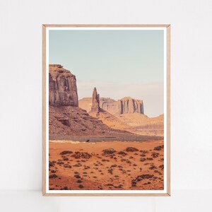 Peut inclure: Une photographie d'un paysage d&eacute;sertique avec des formations rocheuses rouges en arri&egrave;re-plan. Le premier plan est un champ d'herbe s&egrave;che et brune.