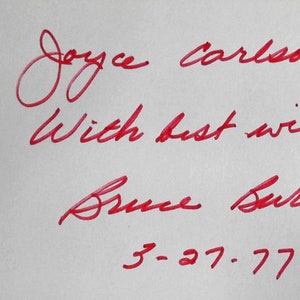Puede incluir: Inscripci&oacute;n en tinta roja en una tarjeta blanca que dice "To Joyce Carlson with best wishes Bruce Burk 3-27-77".