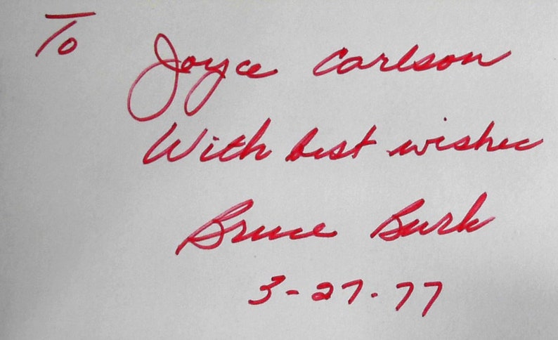 Puede incluir: Inscripci&oacute;n en tinta roja en una tarjeta blanca que dice "To Joyce Carlson with best wishes Bruce Burk 3-27-77".