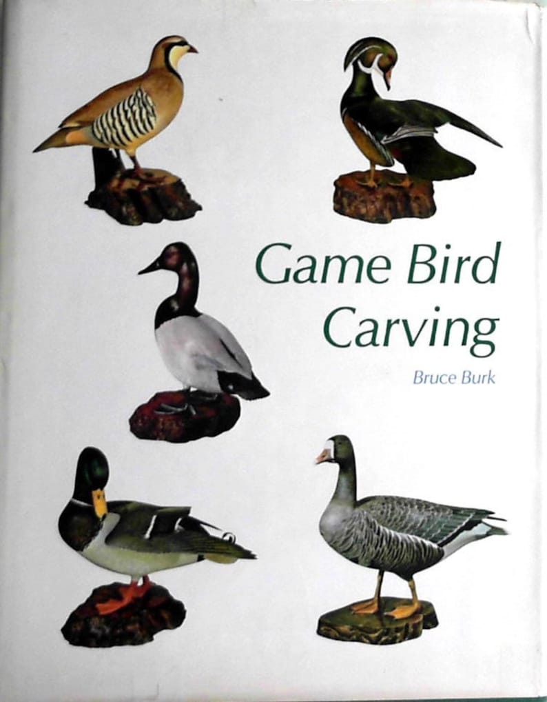 Puede incluir: Un libro titulado "Game Bird Carving" de Bruce Burk, que presenta cinco p&aacute;jaros tallados: una codorniz marr&oacute;n y blanca, un pato de madera verde y blanco, un pato marr&oacute;n y blanco, un ganso gris y blanco y un pato silvestre.