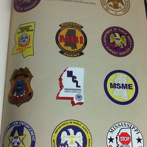 May include: A page with nine different circular and rectangular badges with the text 'Mississippi Department of Public Safety' at the top. The badges are for various departments including the Mississippi Highway Patrol, the Bureau of Investigation, the Department of Public Safety Support Services, the Mississippi Crime Lab, the Mississippi State Medical Examiner, the Mississippi Law Enforcement Training Academy, the Division of Public Safety Planning, and Mississippi Crime Stoppers.
