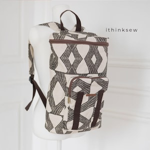 Puede incluir: Una mochila beige y marrón con un diseño geométrico. La mochila tiene un asa superior, un bolsillo frontal y correas ajustables. El texto "ithinksew" es visible en el lateral de la mochila.