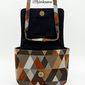 May include: Open, geometric-patterned handbag with a flap closure. The bag features a brown, gray, and orange triangle design on the exterior. The interior is black, and the strap is patterned. The text "iThinksew" is visible.