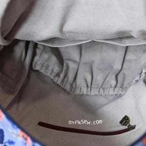 May include: The inside of a blue and floral patterned bag with a zipped pocket and a small fabric tag that says "ithinksew.com".