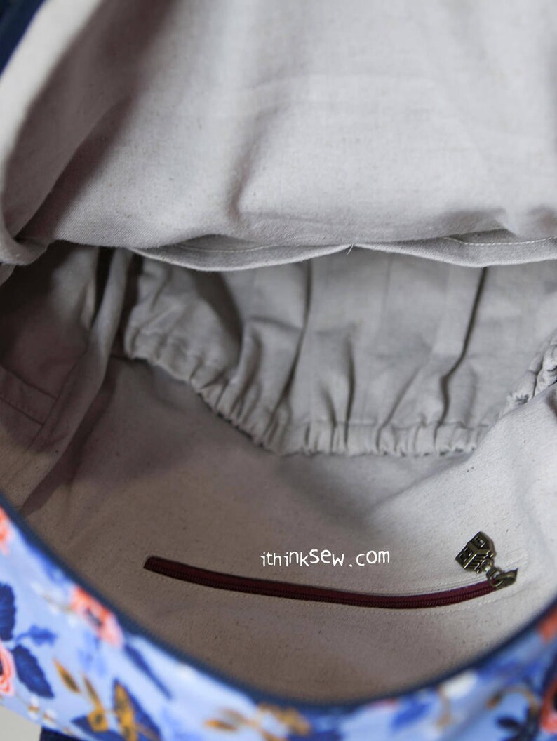 May include: The inside of a blue and floral patterned bag with a zipped pocket and a small fabric tag that says "ithinksew.com".