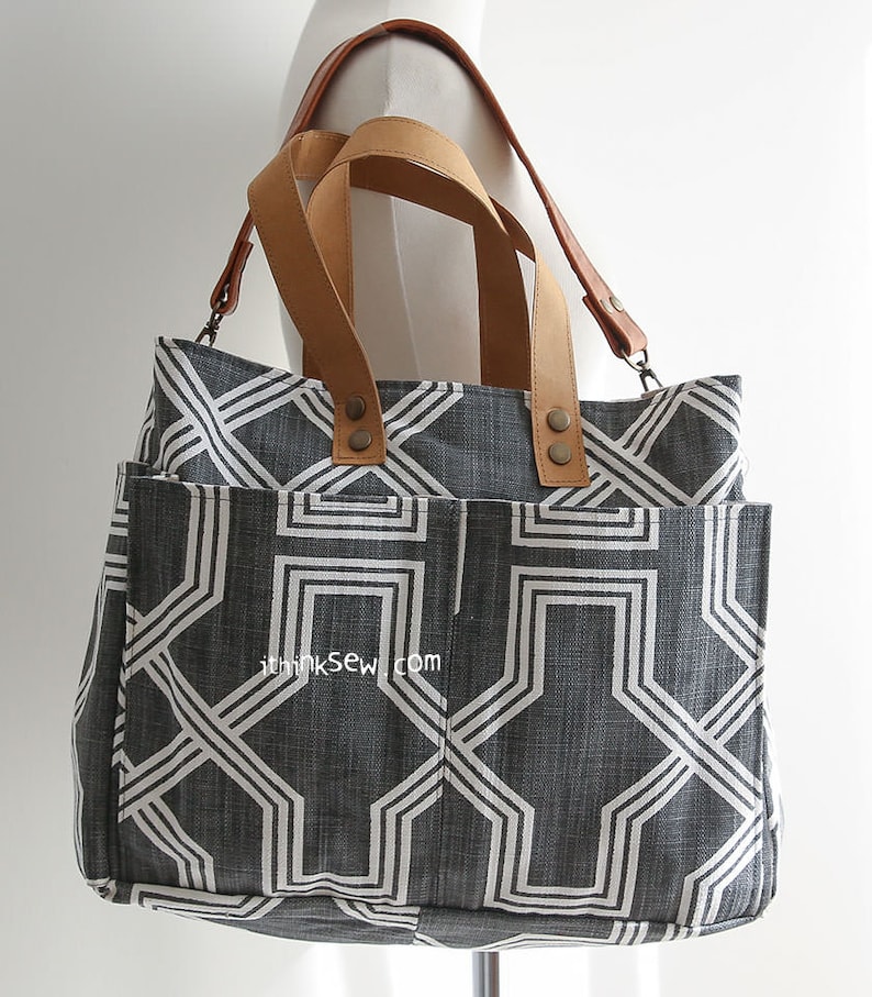 May include: A gray and white geometric patterned tote bag with brown leather straps and metal accents. The bag has a large pocket on the front and the text "ithinksew.com" is printed on the front.