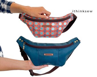 May include: Two fanny packs. The top one has a floral pattern in orange and blue. The bottom one is teal with a brown zipper and strap. Both have a small "HANDMADE" tag.
