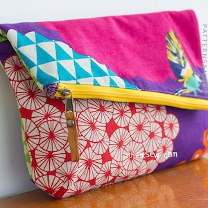 May include: A colorful fabric clutch with a zipper closure. The clutch has a geometric pattern on the front flap and a floral pattern on the back. The text "ithinksew PATTERNS & TUTORIALS" is printed on the right side of the clutch.