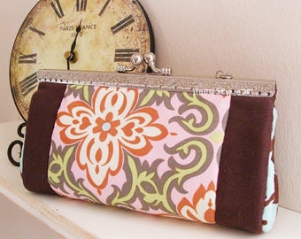 May include: A brown and pink floral fabric clutch purse with a silver metal clasp. The purse has a brown fabric trim and a floral pattern with pink, brown, green, and white colors.