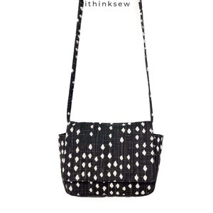 May include: Black and white patterned crossbody bag with a flap closure and a long strap. The bag features a repeating pattern of white diamond shapes on a black background. The text "ithinksew" is printed on the strap.