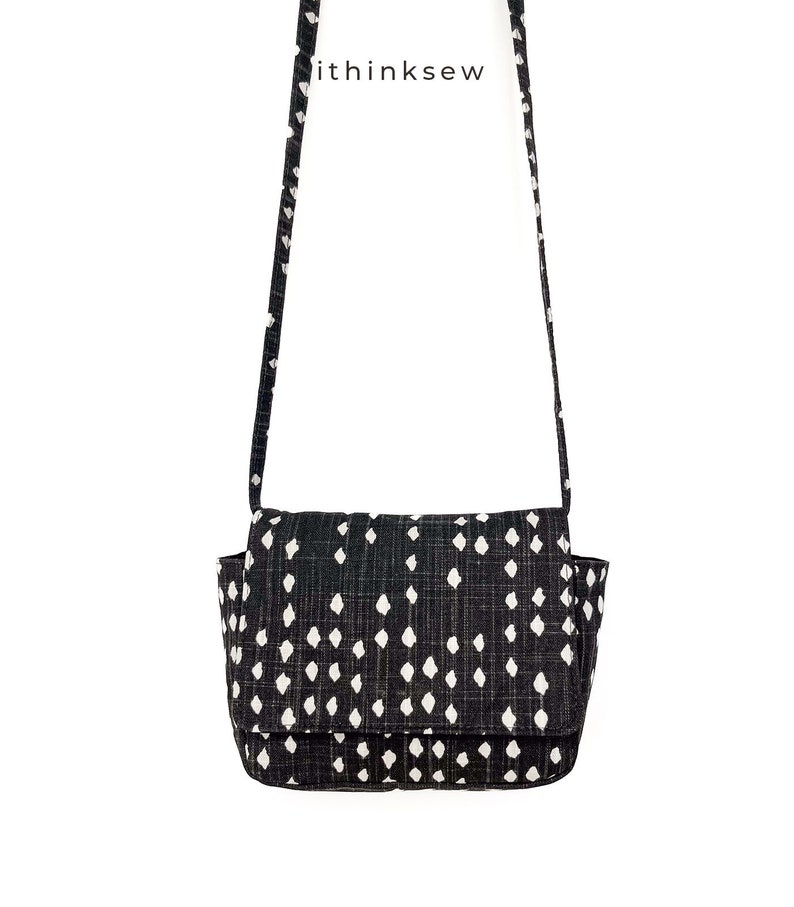 May include: Black and white patterned crossbody bag with a flap closure and a long strap. The bag features a repeating pattern of white diamond shapes on a black background. The text "ithinksew" is printed on the strap.