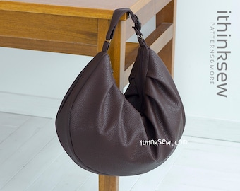 May include: A brown leather hobo bag with a single strap hanging from a wooden table. The bag has a slightly slouched look and is made of a textured leather. The text "ithinksew.com" is visible on the bag.