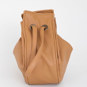 Peut inclure: Un sac seau en cuir de couleur tan avec une fermeture &agrave; cordon et deux poign&eacute;es sup&eacute;rieures.