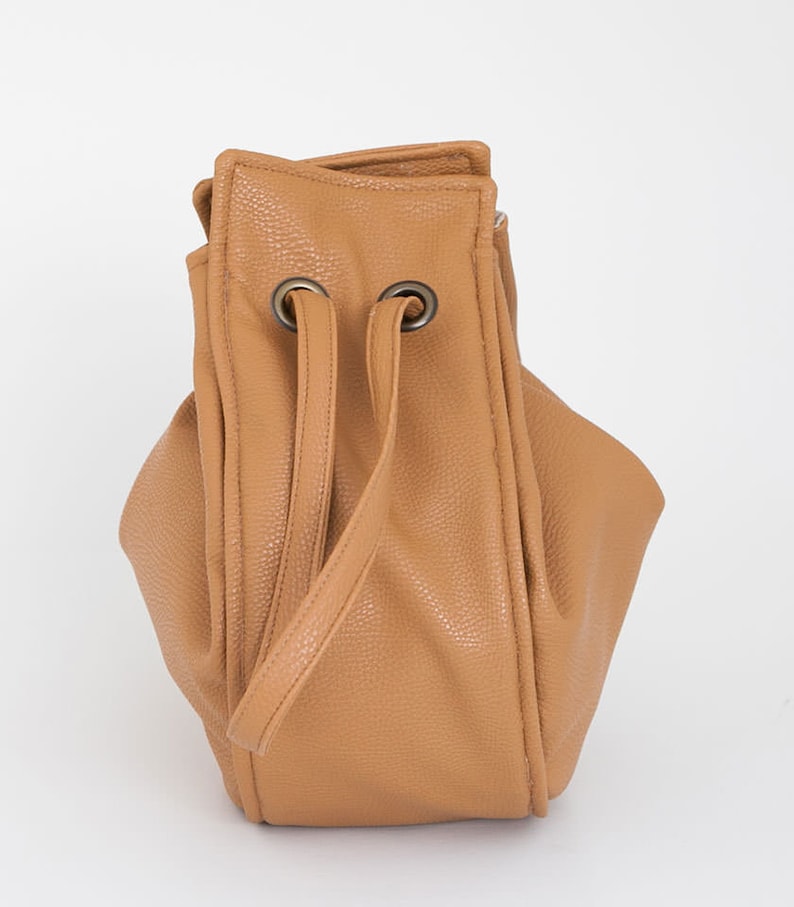Peut inclure: Un sac seau en cuir de couleur tan avec une fermeture &agrave; cordon et deux poign&eacute;es sup&eacute;rieures.