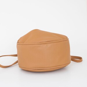 Peut inclure: Un sac seau en cuir marron avec un fond arrondi et une seule bandouli&egrave;re.