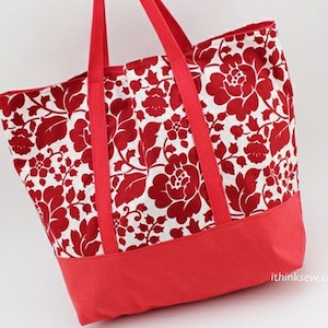 May include: A red and white floral tote bag with a solid red bottom. The bag has two wide straps and a large main compartment.