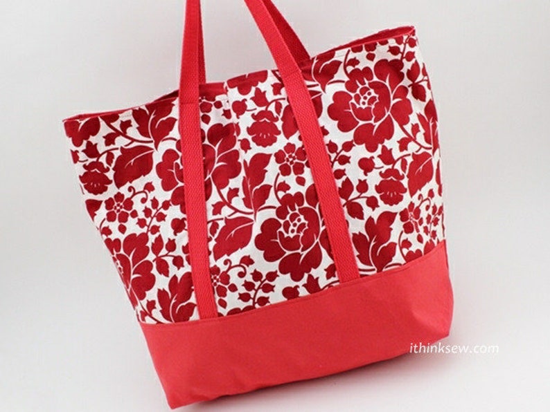 May include: A red and white floral tote bag with a solid red bottom. The bag has two wide straps and a large main compartment.