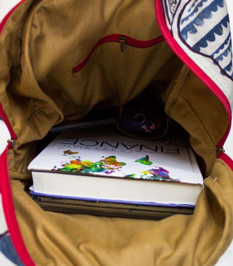 May include: A brown canvas backpack with a red zipper and a blue and white patterned design. The backpack is open and filled with books, including one titled "Introduction to Corporate Finance".