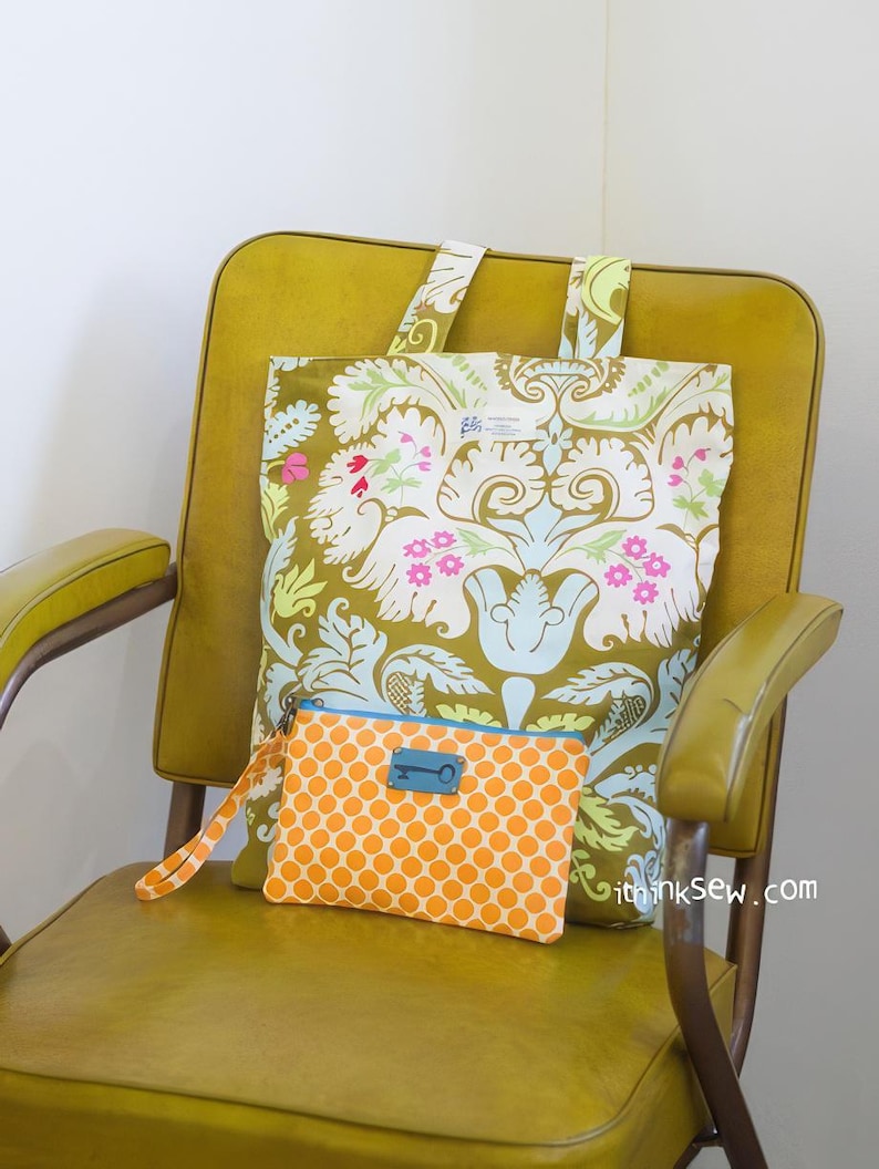 K&ouml;nnte beinhalten: Ein gelber Stuhl mit einer gro&szlig;en Tragetasche mit floralem Muster und einer kleineren orangefarbenen Clutch mit Punkten und einem Schl&uuml;sselanh&auml;nger. Die Tragetasche hat ein blaues und wei&szlig;es Etikett mit der Aufschrift "ithinksew.com".