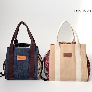 Könnte beinhalten: Zwei Tragetaschen mit braunen Henkeln. Die Tasche links ist jeansblau mit einem braunen floralen Futter. Die Tasche rechts ist beige mit einem burgunderfarbenen floralen Futter. Beide Taschen haben ein braunes Leder-Etikett mit der Aufschrift "handgefertigt".