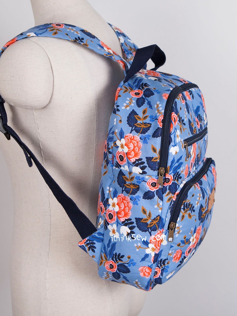 May include: A blue floral backpack with navy blue straps and zips. The backpack has two large compartments and a smaller pocket on the front. The text "thinksew.com" is printed on the bottom of the backpack.