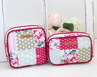 May include: Two patchwork fabric zippered pouches with red trim. The larger pouch has a floral pattern and the smaller pouch has a floral and polka dot pattern. Both pouches have a brown leather tag that says "Hand Made".