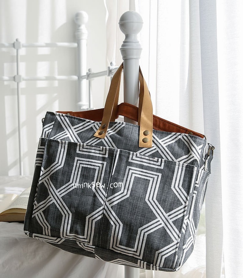 May include: A gray and white geometric patterned tote bag with brown leather handles and a zipper closure. The bag has multiple pockets and the text "thinksew.com" is visible on the front.