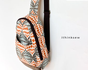 May include: A brown and white patterned crossbody bag with a brown adjustable strap. The bag has a front pocket and a zipper closure. The bag is made of fabric and has a leather trim.