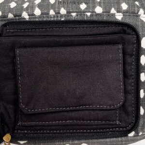 May include: Close-up of a gray and white patterned fanny pack with a black interior pocket. The fanny pack has a zipper closure and a small pocket inside. The text "ithinksew" is printed on the top of the fanny pack.