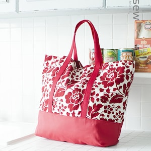 May include: A red and white floral tote bag with red handles. The bag is sitting on a white tiled counter.