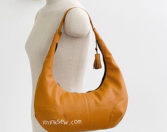 May include: A tan leather hobo bag with a tassel on the strap. The bag is on a white mannequin. The website "ithinksew.com" is printed on the bag.