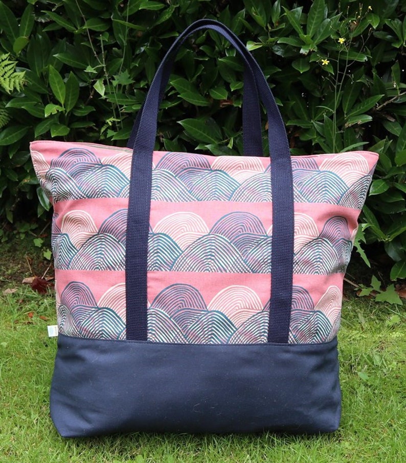 May include: A large tote bag with navy blue straps and a pink and green geometric pattern. The bag has a solid navy blue bottom.