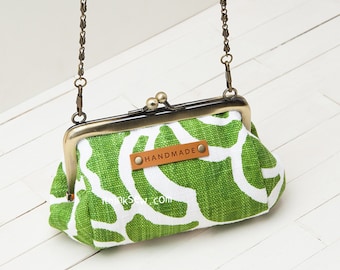 May include: A green and white patterned fabric coin purse with a brass clasp and chain strap. The purse has a brown leather tag that says "HANDMADE".