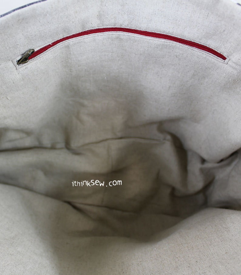May include: The inside of a beige tote bag with a red zipper pocket. The bag has a website address printed on the inside: ithinksew.com
