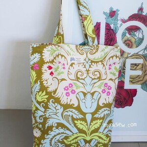 K&ouml;nnte beinhalten: Eine gr&uuml;ne Einkaufstasche mit Blumenmuster. Die Tasche hat ein wei&szlig;es Etikett mit dem Text "Made in Italy". Die Tasche liegt auf einer wei&szlig;en Oberfl&auml;che.