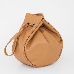 Peut inclure: Un sac seau en cuir marron avec une fermeture &agrave; cordon et une seule sangle.