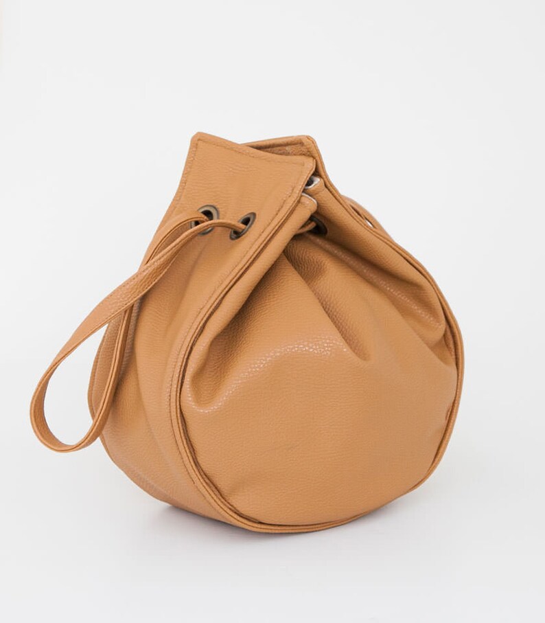 Peut inclure: Un sac seau en cuir marron avec une fermeture &agrave; cordon et une seule sangle.
