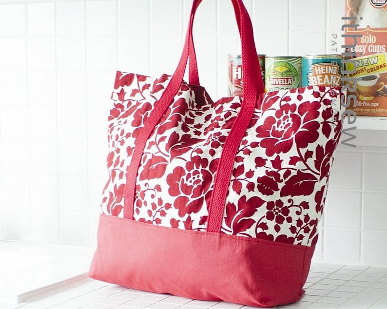 May include: A red and white floral tote bag with red handles and a solid red bottom. The bag is made of fabric and has a large capacity.