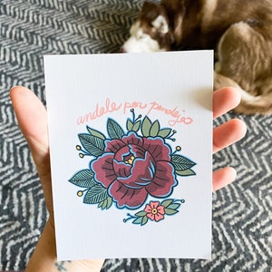 May include: A white card with a pink floral design and the text "andale por pendejo" in pink.