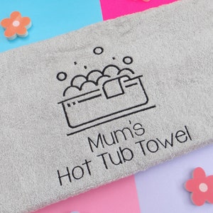 May include: Grey bath towel with black embroidery of a hot tub with bubbles and the text "Mum's Hot Tub Towel".