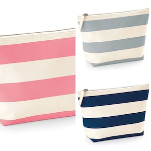 May include: Three striped zippered pouches. The pouches are made of canvas and have a white background with colored stripes. The pouches are pink, light blue, and navy blue.